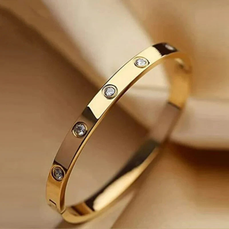 Gold bracelet with embedded diamonds on a beige background
