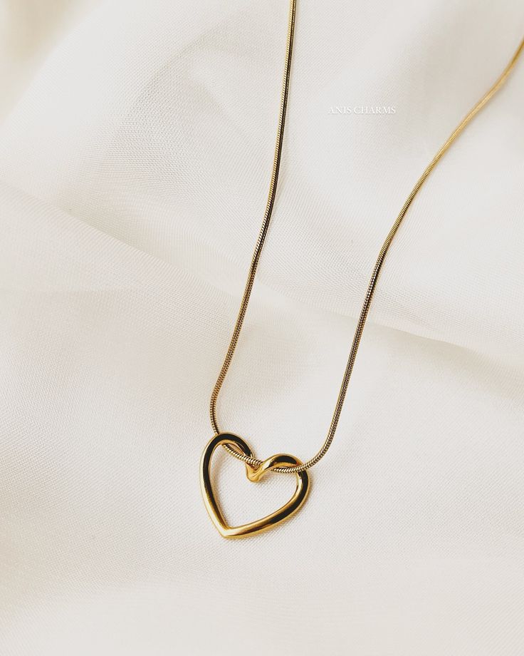 Gold heart-shaped necklace on a light beige fabric background