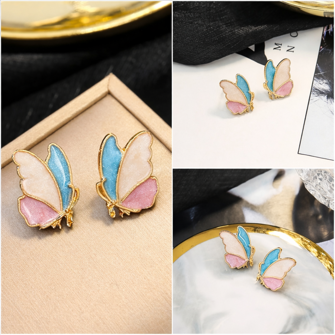 Butterfly-shaped earrings with pink and blue wings on a gold surface.