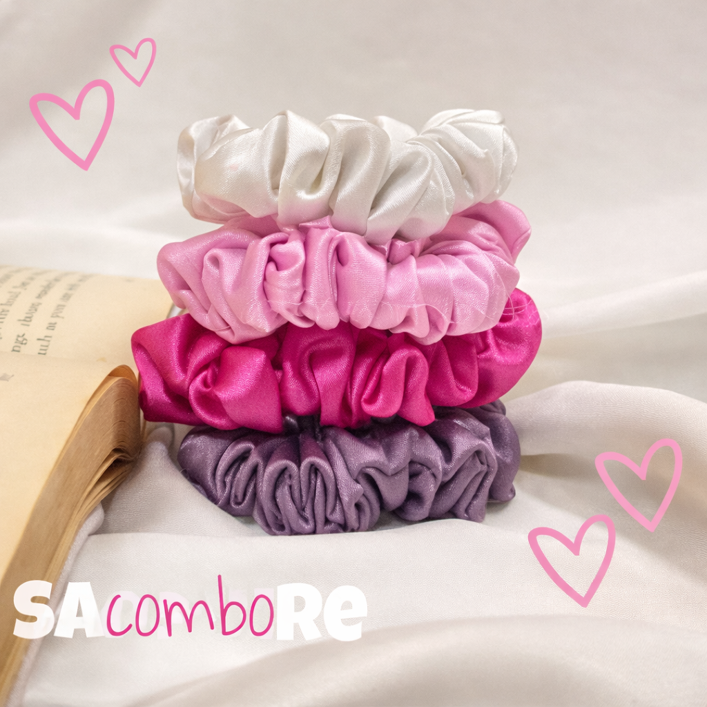 “Stack of four satin scrunchies in white, light pink, deep pink, and lavender, neatly arranged on soft white fabric beside an open book, with pink heart doodles around them for a cute, aesthetic look.”