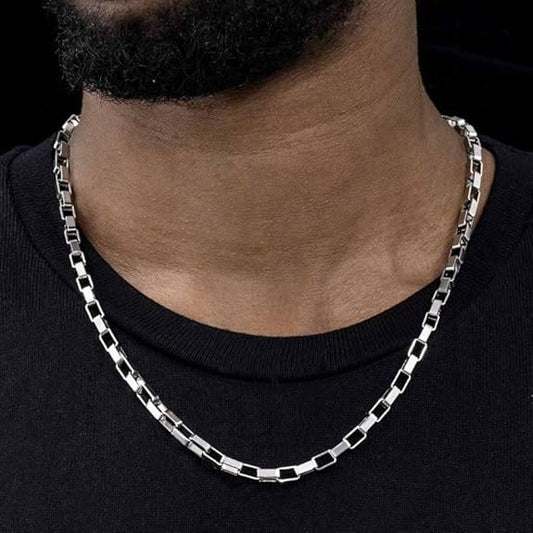 Silver chain necklace on a person wearing a black shirt against a dark background