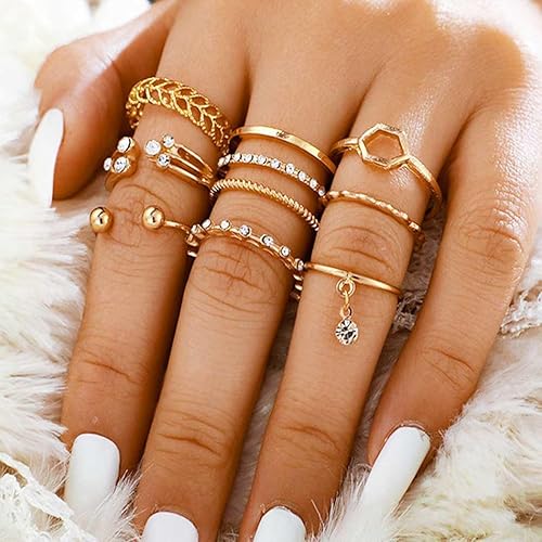 Close-up of a hand wearing multiple gold rings on a soft white background