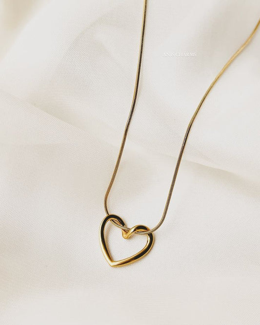 Gold heart-shaped necklace on a light beige fabric background