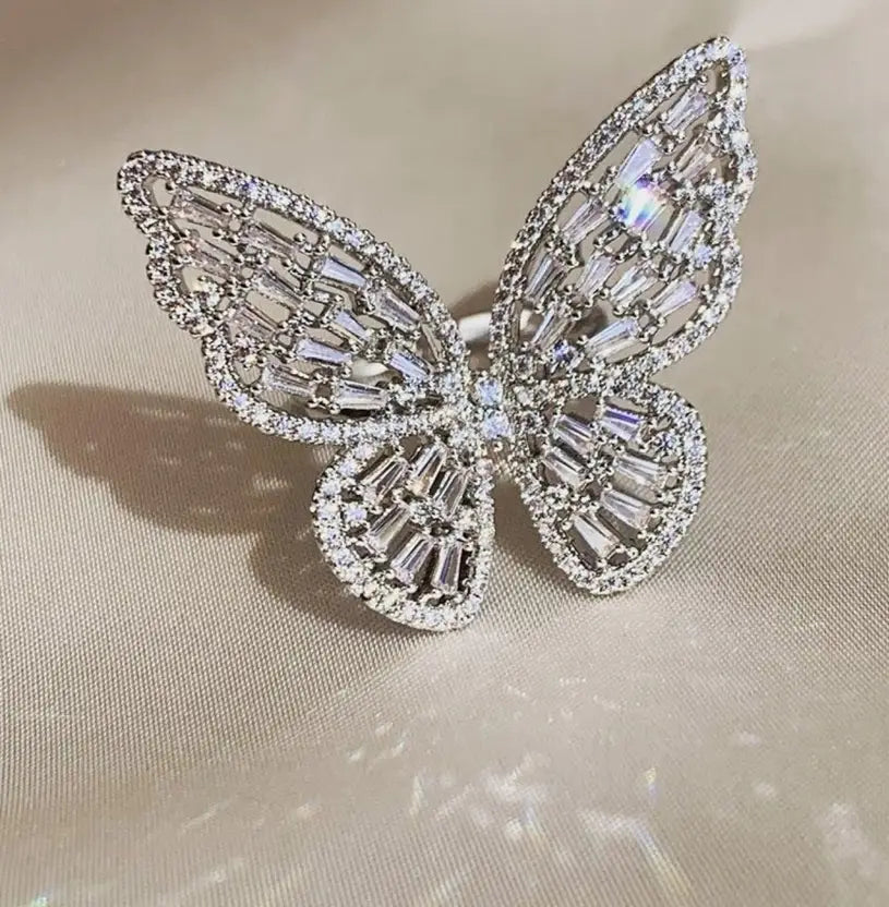 Butterfly-shaped jewelry with crystal-like stones on a beige fabric background