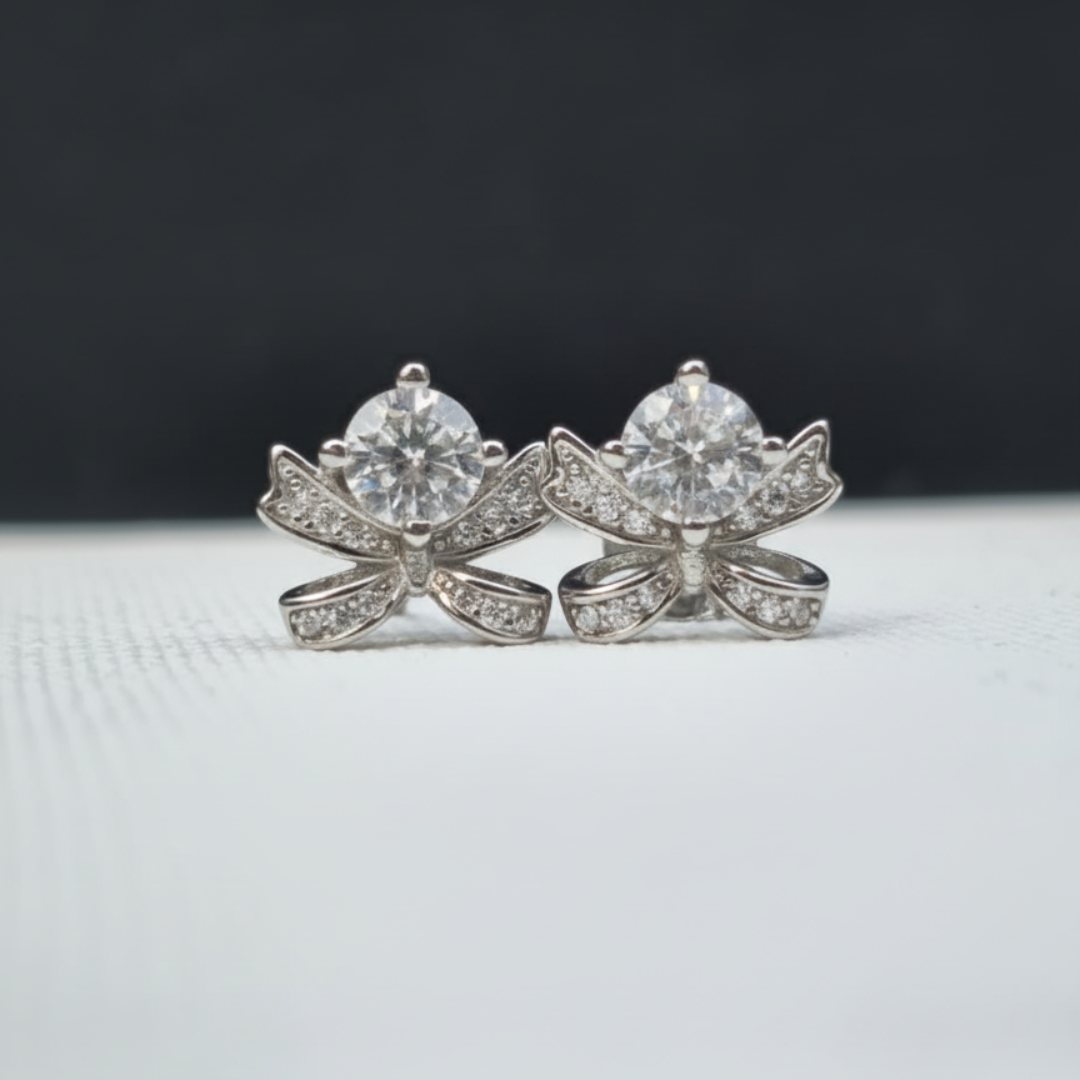 Pair of diamond earrings on a light gray surface with a dark background