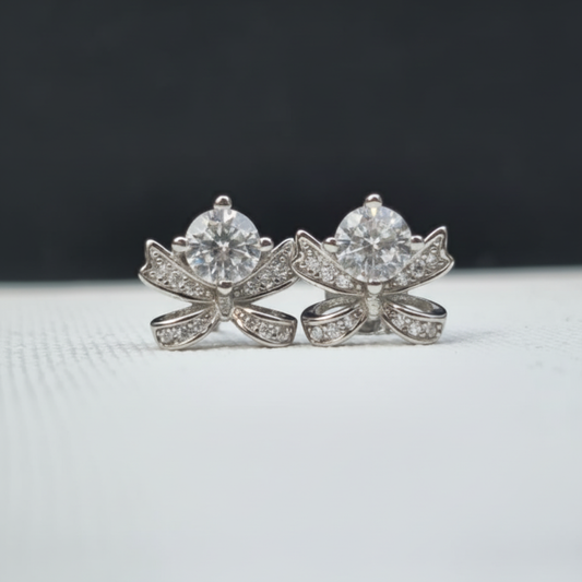 Pair of diamond earrings on a light gray surface with a dark background