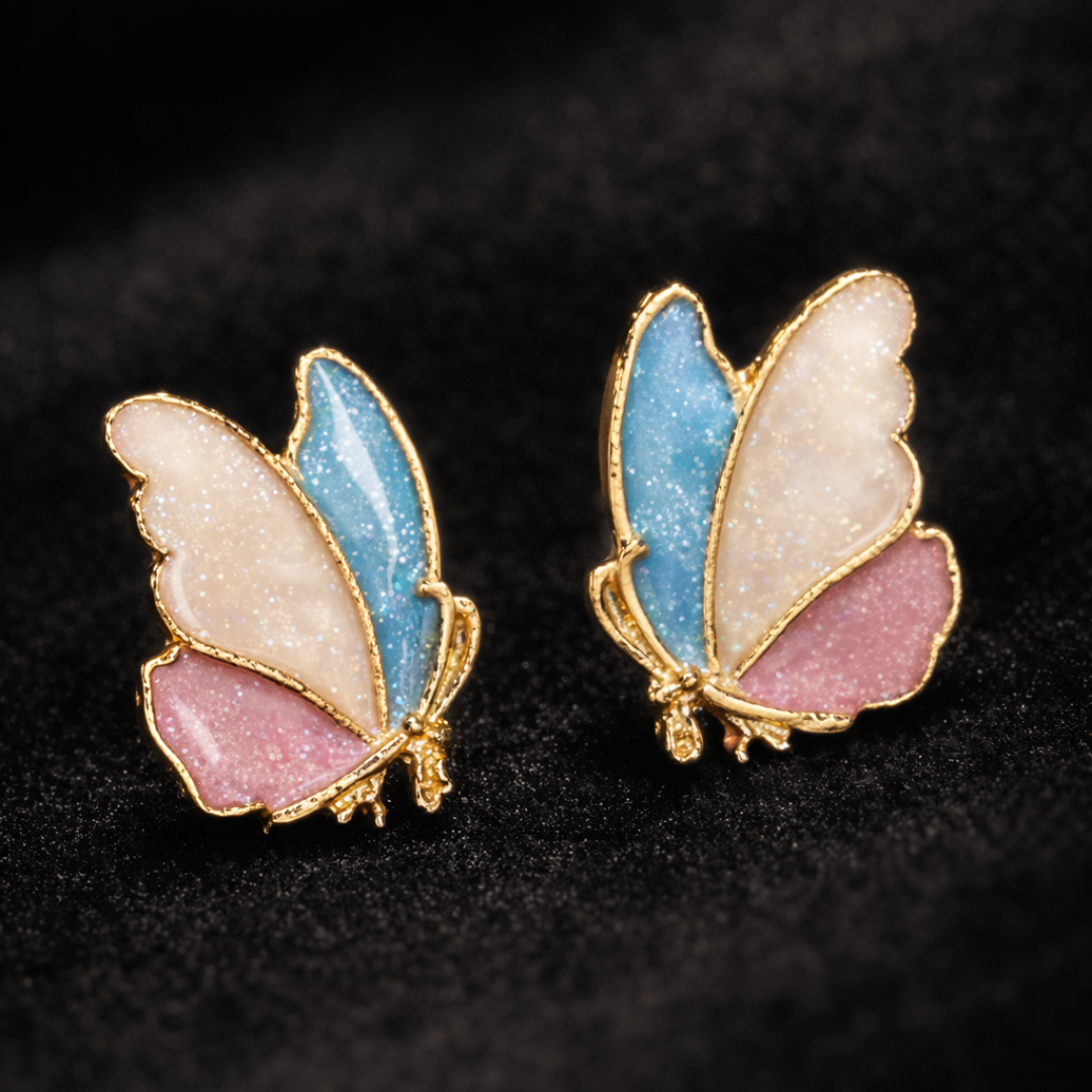 Butterfly-shaped earrings with gold frames, blue and pink wings on a black background