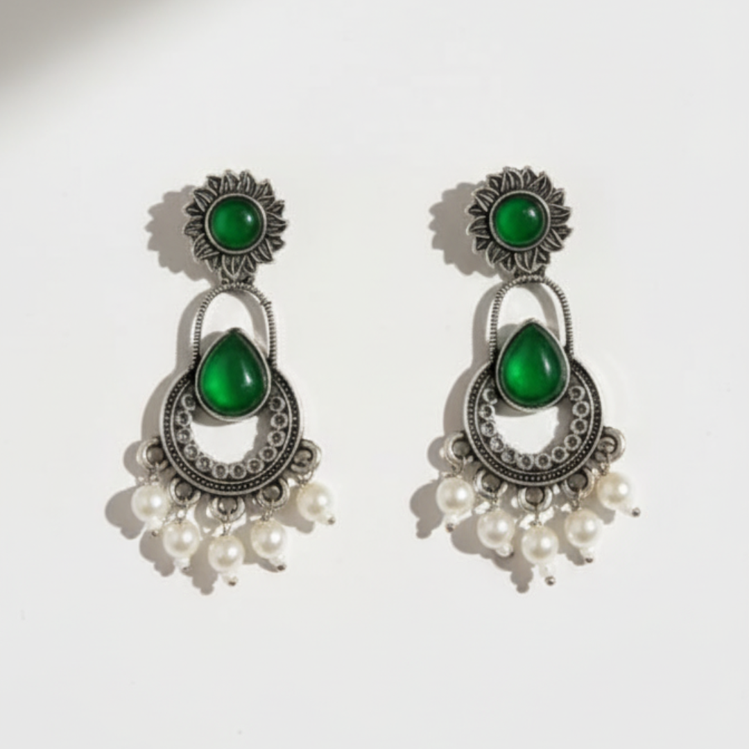 Pair of earrings with green stones and pearl-like beads on a white background