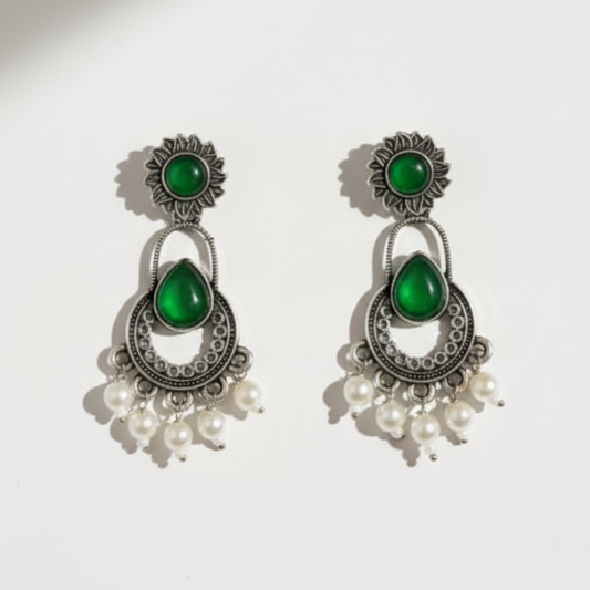 Pair of earrings with green stones and pearl-like beads on a white background