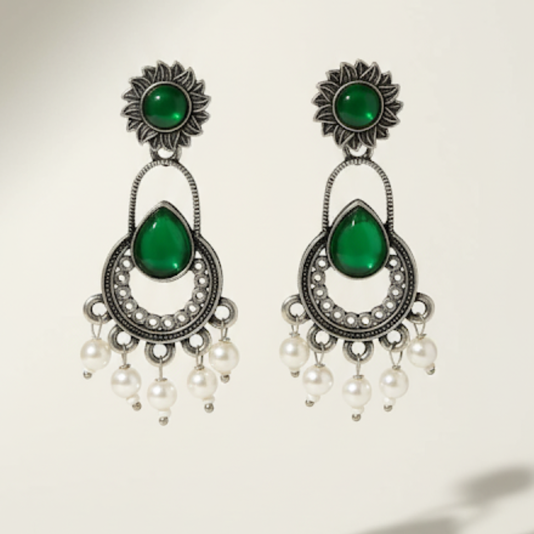 Pair of earrings with green gemstones and pearl-like beads on a light background