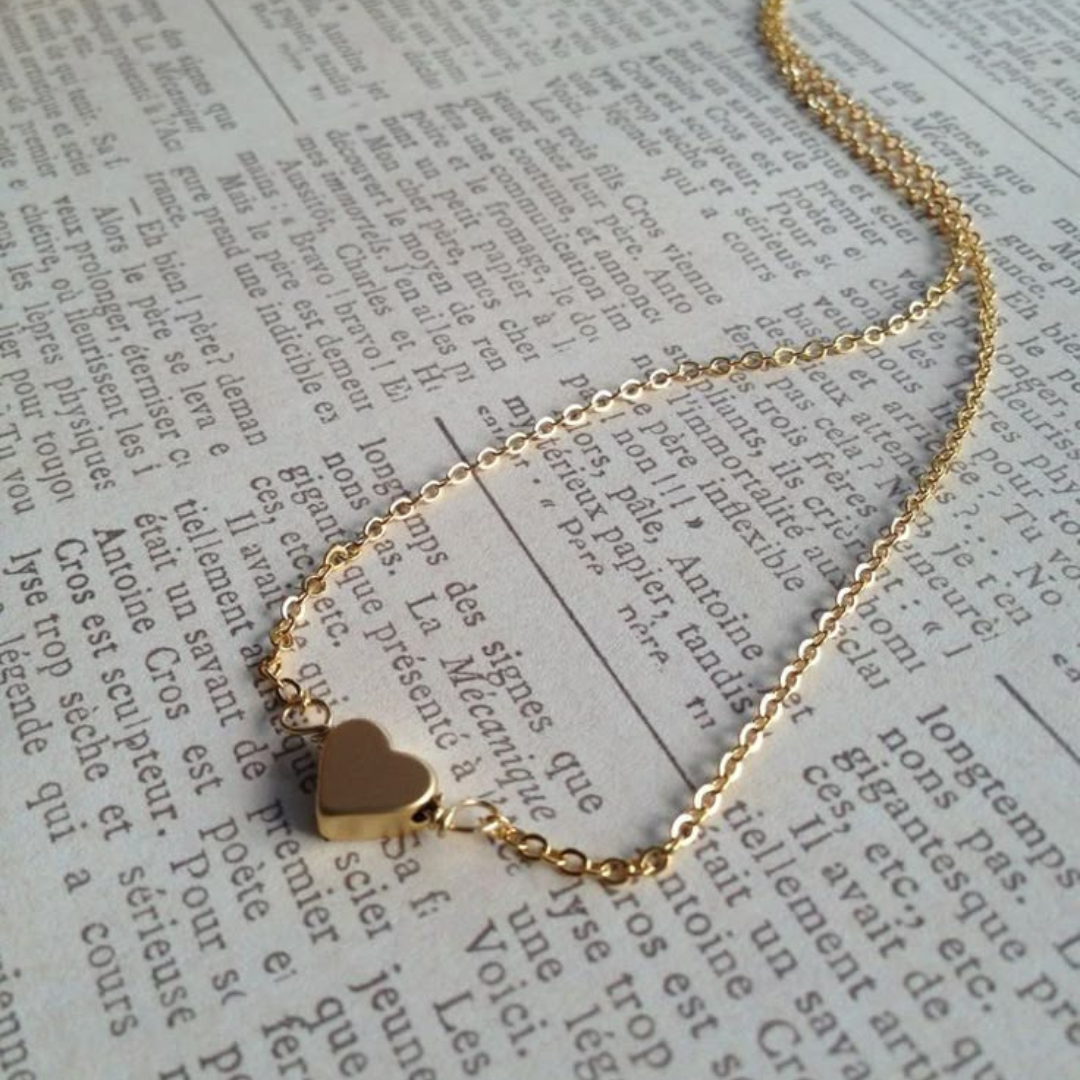 Gold necklace with a heart pendant on a piece of text.