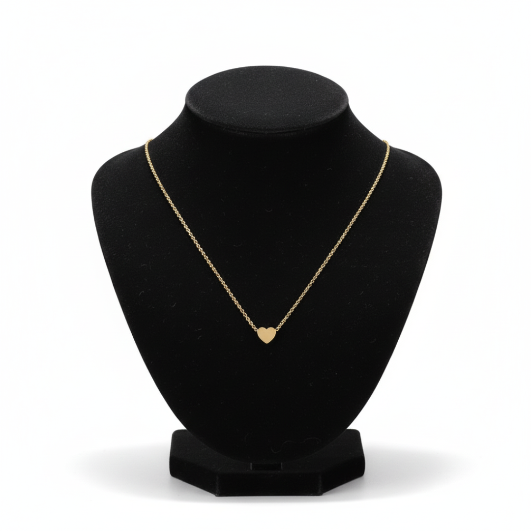 Gold necklace with a heart pendant on a black bust against a white background