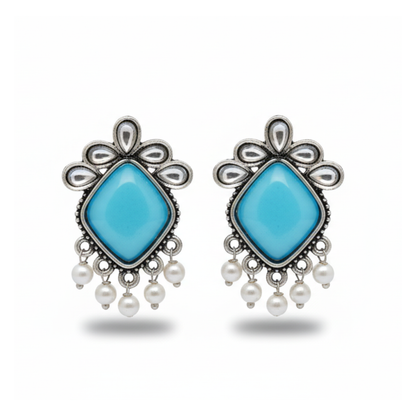 Pair of earrings with turquoise stones and pearl accents on a white background