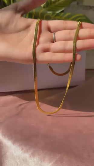 A video showing a gold snake chain for men displayed on hand under natural light, highlighting its sleek and stylish design.